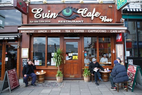 People sit outside Evin Cafe Bar next to two low barrel-style tables eiqrkituidquinv