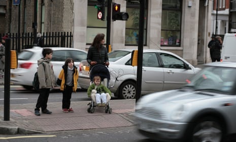 Children cross the road in heavy traffic outside their school in Hackney, London