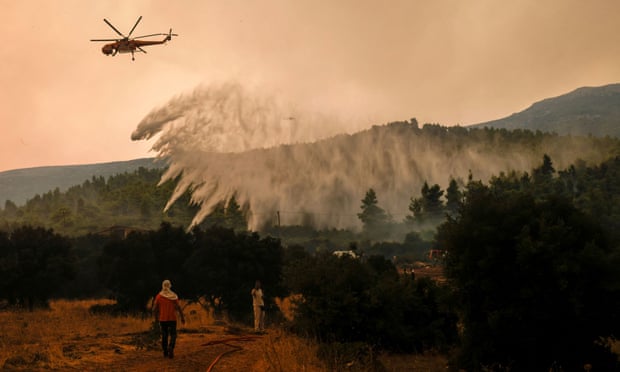A firefighting helicopter makes a water drop as a wildfire burns in the village of Vilia, Greece, on August 18, 2021.