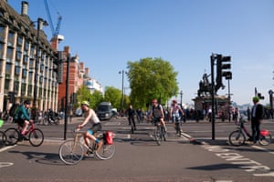 People on bicycles in London under a blue sky