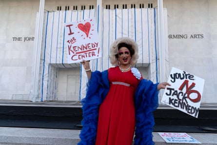 A drag queen holds up some protest signs