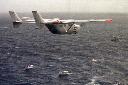 an airplane flies over small boats in the sea
