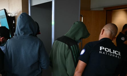 Men wearing hoodies are guided into court by an officer of the Police National