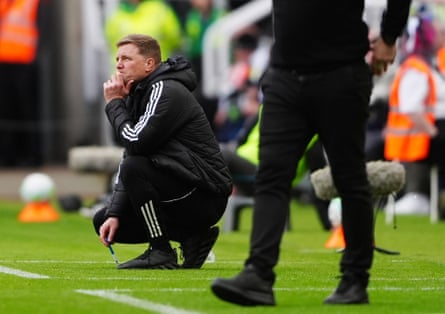 Eddie Howe kneels on the sideline during a Newcastle match.