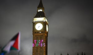 A Palestinian flag flaps in the air while a message reading 'Stop bombs' is projected on Big Ben at Westminster