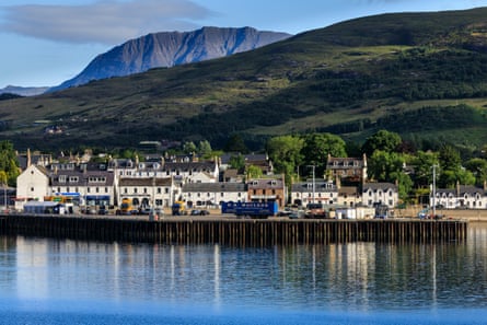 Houses with a loch in front and hills behind.