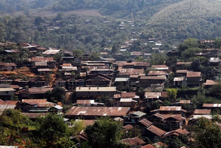 A view of Umpiem Mai refugee camp, a clustered collection of brown coloured roofs with wooded hills in the distance.