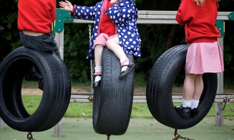 Three schoolchildren balance on tyres in a playground
