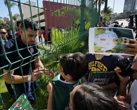 Group of young boys at fence with Mehdi Taremi on other side signing autographs