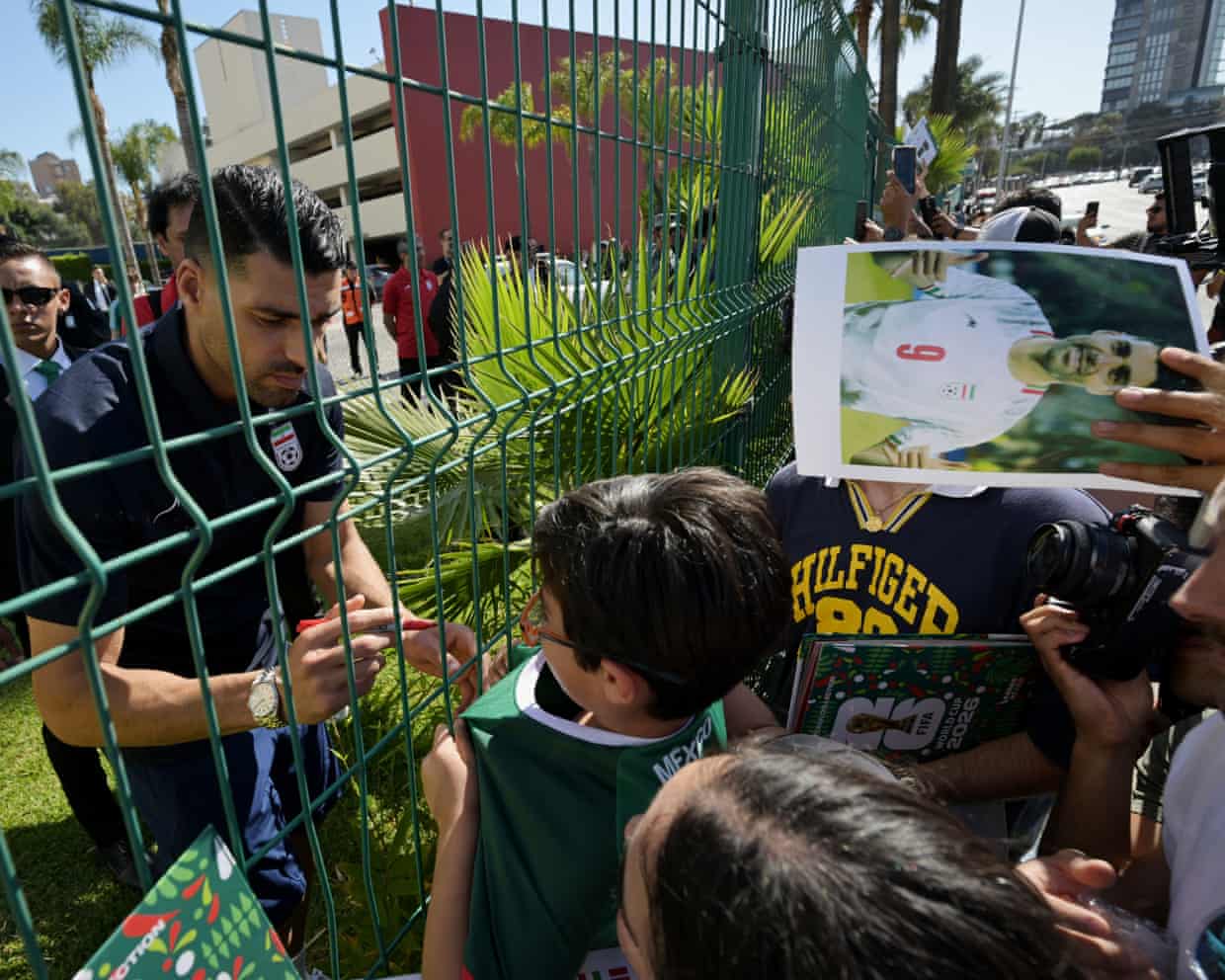 Group of young boys at fence with Mehdi Taremi on other side signing autographs