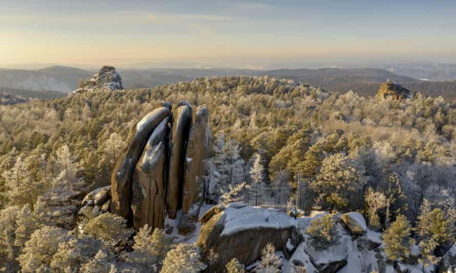 Rock formations capped with snow, surrounded by forests
