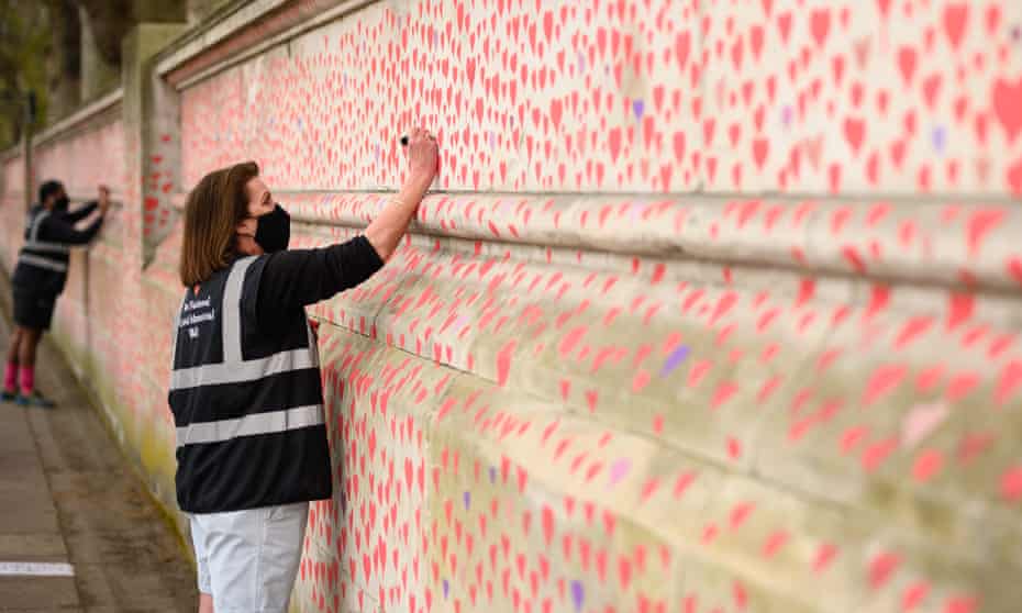 A volunteer adds hearts to the Covid-19 memorial wall outside St Thomas’ hospital in London.