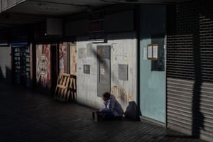 Northampton, England. A homeless woman begs outside boarded-up shops