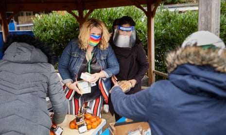 The headteacher of Mora primary school, Kate Bass, wears a rainbow mask as she hands out meals to parents at the school in Cricklewood, north London.