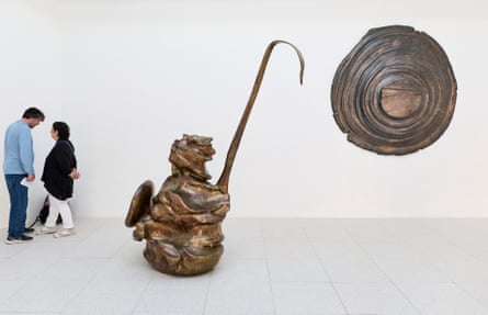 Two abstract sculptures in a white room. Two visitors are stood to the side