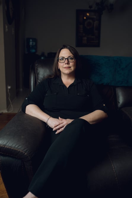 A middle-aged white woman sitting on a sofa looks at the camera