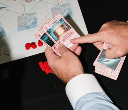 The hands of a war-gamer holding cards above a table with a map on it
