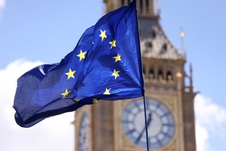 The EU flag at full mast fluttering in the wind with the clock tower of the palace of Westminster in the background