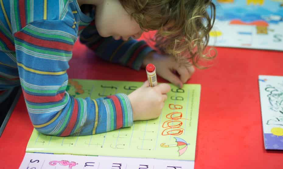 A young girl writes letters at a playgroup for pre-school aged children