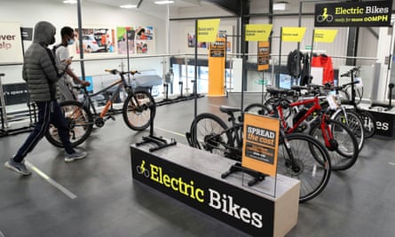 Customers wearing face masks walk past electric bikes in a Halfords store in Luton