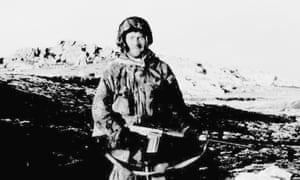 Falkland Islanders At War-P21.tif仍然穿着战斗服装并配备自动步枪,Terry Peck(岛前警察局长)站在Mount Longdon山坡上