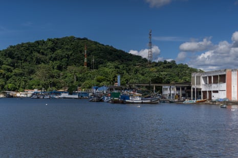 Barcos de pesca ancorados em cais em um pequeno porto com uma encosta verde ao fundo