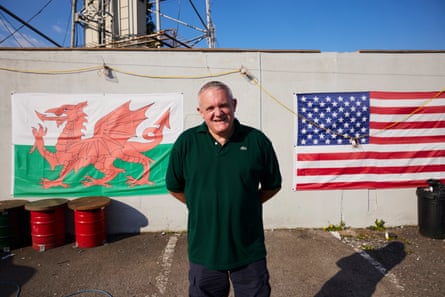 Michael Hett stands in front of the Welsh and US flags.