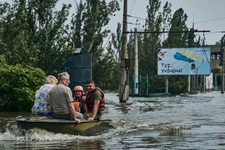 Los trabajadores de emergencia evacuan a los residentes en un bote de un vecindario inundado en Kherson.