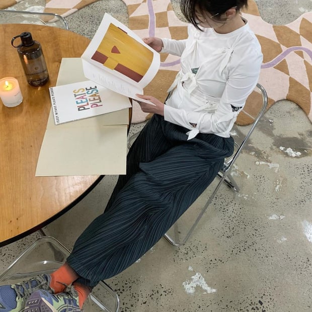 Shifting Worlds staff member Su wearing Issey Miyake Pleats Please pants on the shop floor.