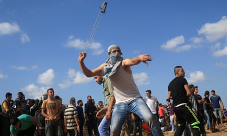 A protester uses a slingshot to throw stones