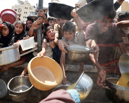 Palestinians wait to receive food from a charity kitchen in Gaza City
