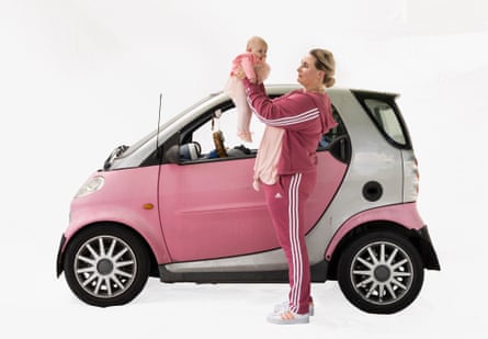 Restaurant manager Frauke and Zora with a Smart car in Delft, Netherlands. She is stood outside the car holding baby Zora