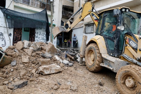 Palestinian men and children watch as an excavator removes rubble from a damaged road, in the aftermath of an Israeli raid in Nur Shams camp, in Tulkarm, in the Israeli-occupied West Bank.