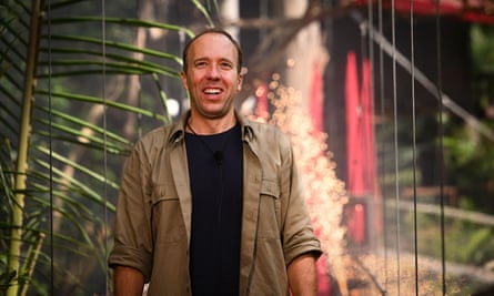 Matt Hancock wearing a khaki shirt with rolled-up sleeves and a black T-shirt, standing in a forest.