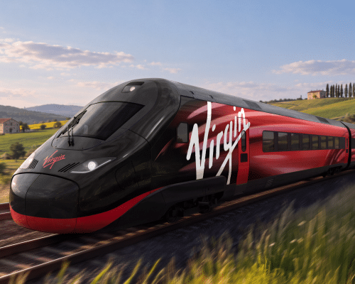 Элегантный черно-красный поезд компании Virgin мчится по рельсам через зеленую сельскую местность.