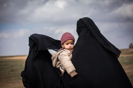 A woman clutching her young child is seen at a civilian screening point for ISIS families fleeing heavy fighting in the city of Baghuz, on 9 February 2019