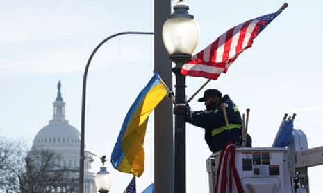A worker installs Ukrainian and US flags near the US Capitol.