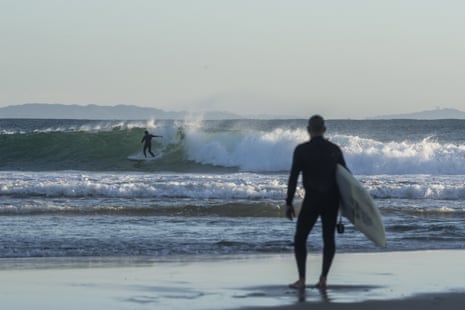 A man watches as another surfer rides a wave at The Pass on June 12, 2020 in Byron Bay, Australia. 