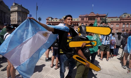 Javier Milei supporters pose with cardboard chainsaws outside the National Congress