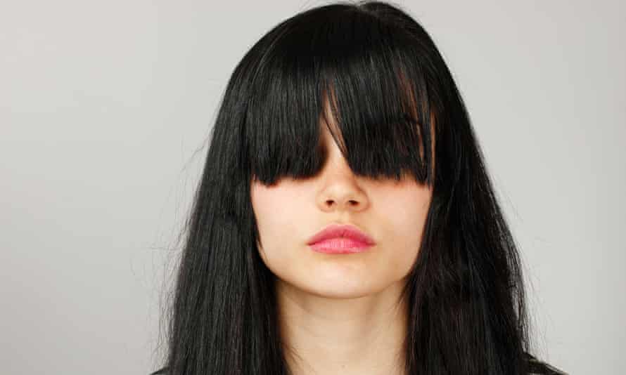 Sad young girl hides her face with bangs
