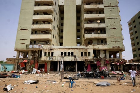 A man walks past near a damaged car and buildings at the central market in Khartoum North.