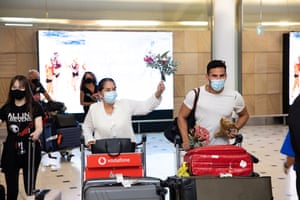 People wearing masks push luggage trolleys as they arrive at Sydney international airport as tourists are now permitted to enter the country after the federal government relaxed border restrictions