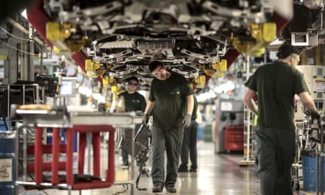 Employees work underneath Jaguar automobiles on the final assembly line at Tata Motors Ltd.’s Jaguar assembly plant in Castle Bromwich