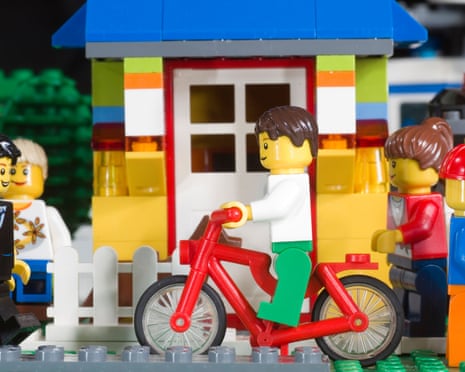 various legos riding a bike, walking and standing near a lego house
