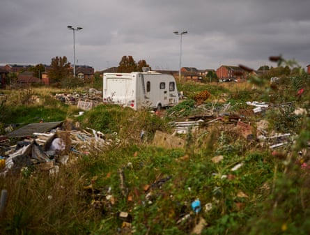A caravan is parked in field of rubbish