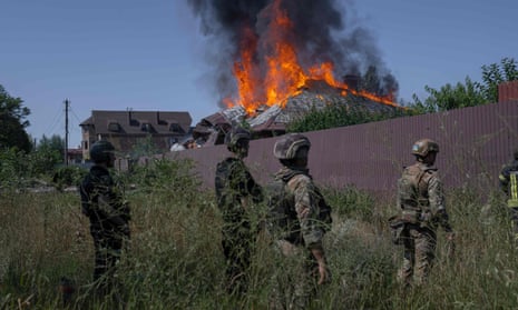 Ukrainian soldiers stand in front of a burning house hit by a shell in the outskirts of Bakhmut.