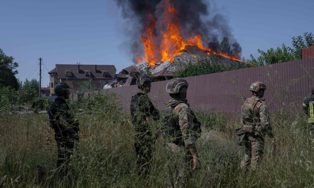 Ukrainian soldiers outside a burning house hit by a shell in the outskirts of Bakhmut