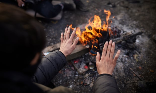 Man warming hands by open fire