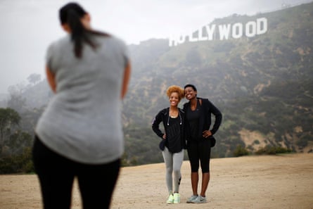 Hikers pose for a photo in front of the Hollywood sign on a foggy day.