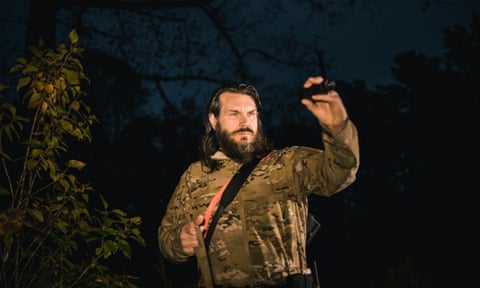 Man in camouflage holds flashlight outside